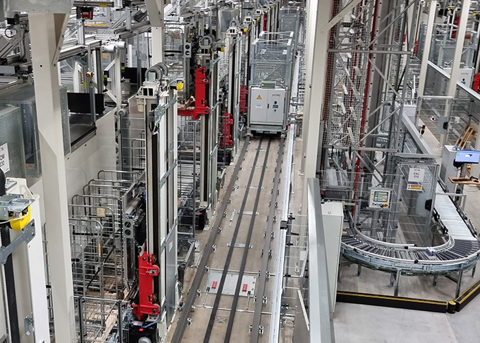 Automated transfer car powered by conductor rail in a warehouse transport
