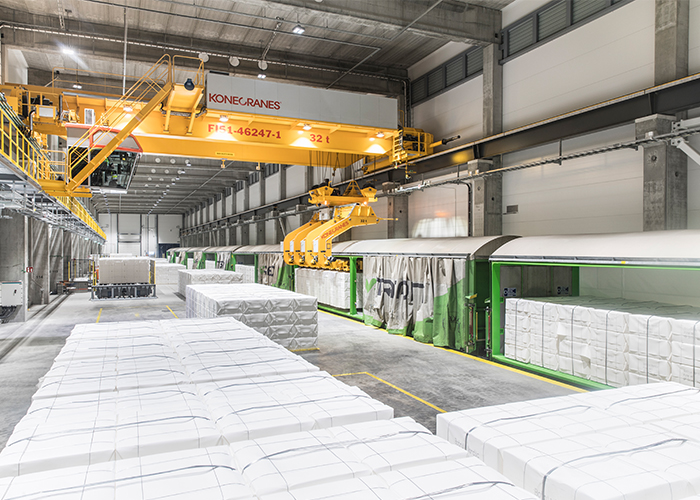 Overhead crane moving material bundles inside a warehouse facility.