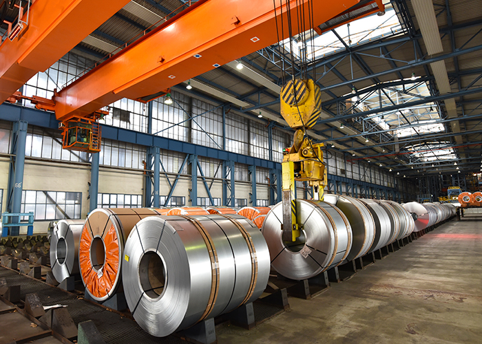 Steel coils stored in a steel processing facility with an overhead crane.