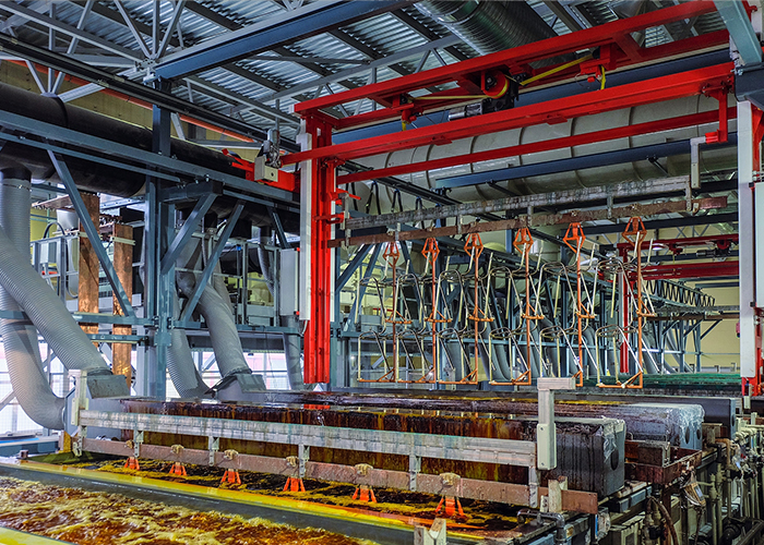 Overhead transport system moving metal components through a galvanizing process in a manufacturing plant.